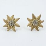 Pair of gold-tone flower-shaped stud earrings with diamond cluster centers on a white background