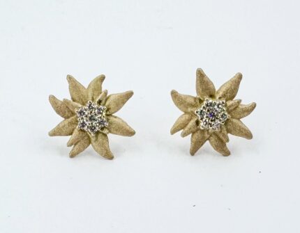 Pair of gold-tone flower-shaped stud earrings with diamond cluster centers on a white background