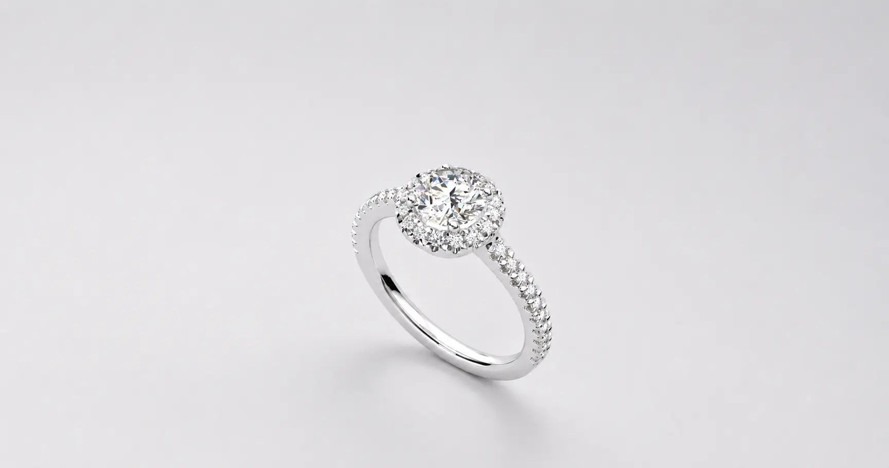 Engagement ring with a central diamond in a halo setting and a pavé diamond band on a silver band backdrop
