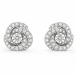 Pair of spiral diamond stud earrings with a central round diamond and pavé-set diamonds along the spirals, in white metal.