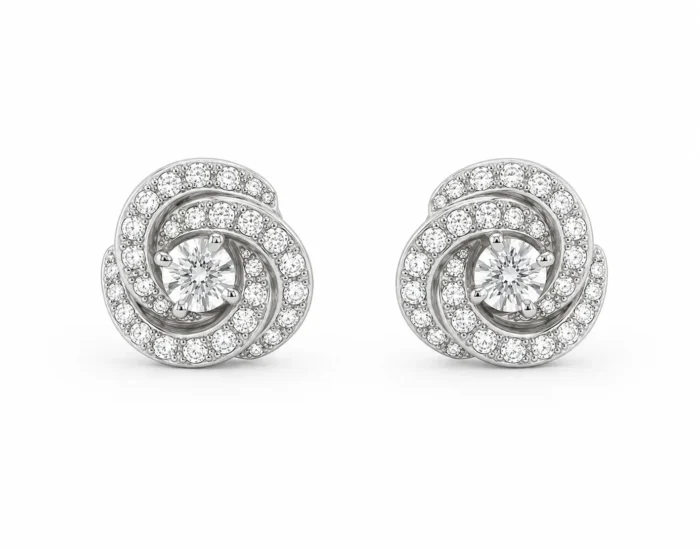 Pair of spiral diamond stud earrings with a central round diamond and pavé-set diamonds along the spirals, in white metal.