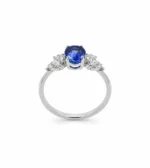 Engagement ring with a vivid blue sapphire center stone flanked by diamond accents on a white-gold band.