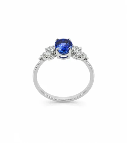 Engagement ring with a vivid blue sapphire center stone flanked by diamond accents on a white-gold band.