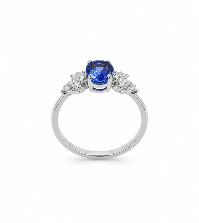 Engagement ring with a vivid blue sapphire center stone flanked by diamond accents on a white-gold band.