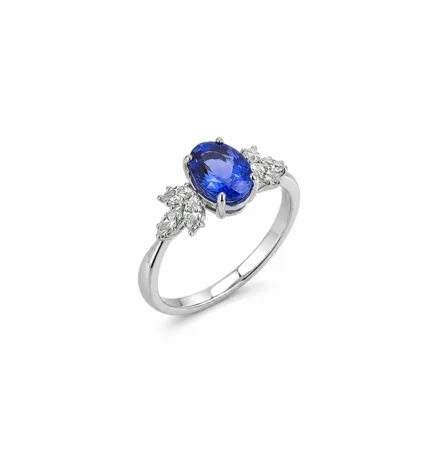 Silver ring featuring an oval blue sapphire centerpiece flanked by diamond clusters on a polished band.