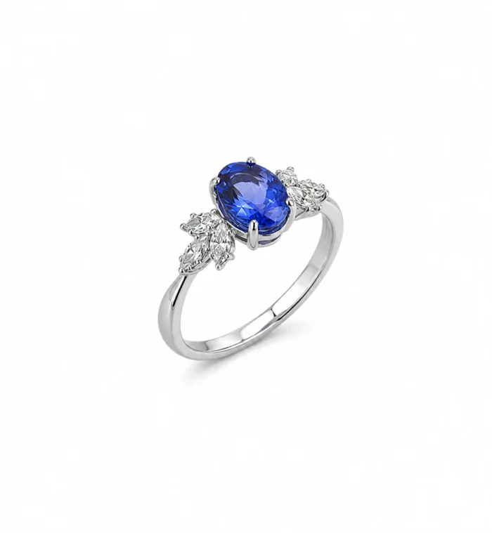 Silver ring featuring an oval blue sapphire centerpiece flanked by diamond clusters on a polished band.