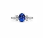 Silver ring with a deep blue oval sapphire centerpiece flanked by diamond leaf accents on each side.