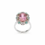 Elegant silver ring with a large pink oval gemstone surrounded by pavé diamonds and small turquoise accents, on a white background.