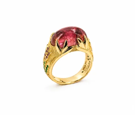 Gold ring with a large pink gemstone set in a vine-inspired filigree band.