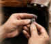 Jeweler’s hands shaping a small silver ring; ring sketches lie on parchment nearby.
